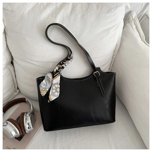 Detail of black tote bag with white contrast stitching and decorative geometric silk scarf
