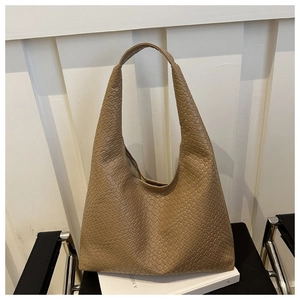 Détail du sac hobo tissé de haute qualité en cuir beige sur une chaise de bureau minimaliste