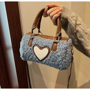 Macro view of plush light blue lamb wool cylinder bag with white heart leather patch detail