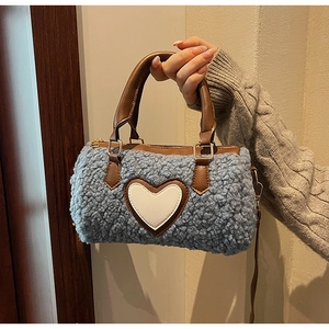 Detail of blue faux shearling barrel bag with white heart patch and brown leather trim