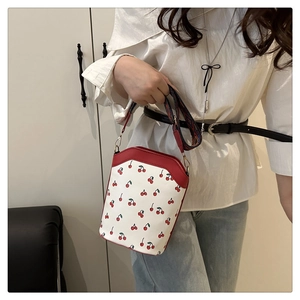 Dettaglio borsa con ciliegie con bordo rosso e tracolla colorata in stile etnico