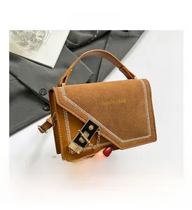Detail view of brown matte small square bag with stitching, lock buckle, and chain strap
