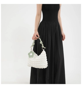 Close-up of white bubble texture fabric with green knotted handle and floral charm