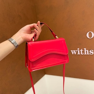 Bright red patent leather handbag with wave-cut flap and adjustable shoulder strap