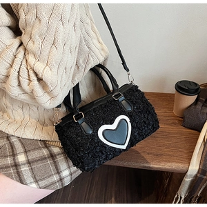 Close-up of black fuzzy lamb wool pillow bag with white heart pattern and leather handle