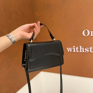 Minimalist black PU leather crossbody bag with gold hardware and curved flap design