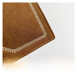 Detailed macro view of brown suede shoulder bag featuring decorative white V-stitch seams