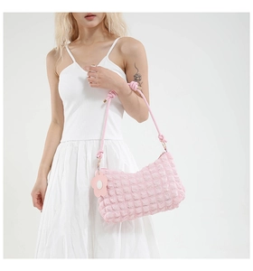 Detail of pink bubble texture cylinder bag with floral charm and knotted shoulder strap