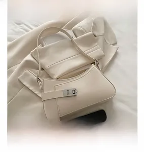 Detail view of cream beige half-moon bag with silver buckle on a beige blazer