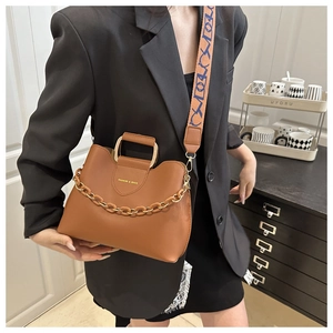 Detail of a brown leather bucket bag with gold chain and woven wide shoulder strap