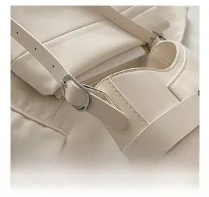 Detail view of adjustable strap with silver buckle on cream saddle bag craftsmanship