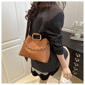Detail of caramel faux leather bucket bag featuring gold metal handle and chain link strap
