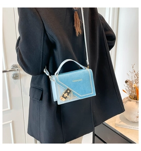Close-up of light blue chain bag with gold lock buckle and asymmetrical flap detail