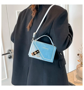 Detail of light blue crossbody bag with gold chain lock on a black wool coat