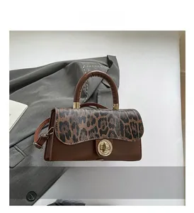 Detail of leopard print flap and gold clasp on brown faux leather crossbody bag