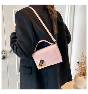 Detail view of pink crossbody bag with V-shaped stitching and golden metal buckle
