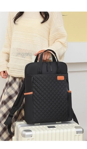 Détail d'un sac à dos de voyage noir matelassé posé sur une valise rigide