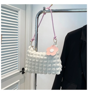 Detail of white bubble textured tote bag with pink rope handles and flower charm