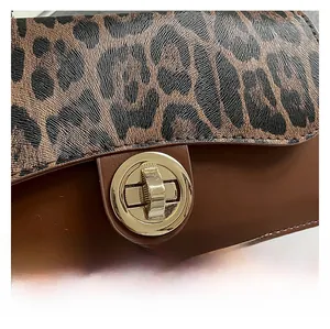 Close-up of leopard print patchwork flap bag featuring a round golden metallic twist lock