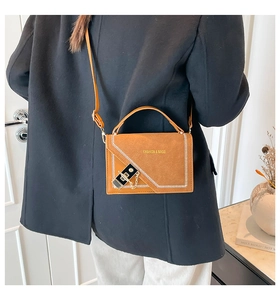 Detailed view of caramel suede crossbody bag with white stitching and gold chain lock