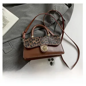 Detail of leopard print crossbody bag with gold round twist lock on grey fabric