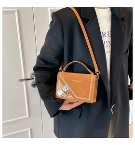 Detail of brown suede shoulder bag with gold chain lock and contrast stitching