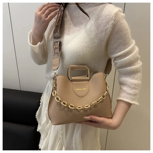Detail of beige bucket bag featuring a decorative thick chain and geometric print strap