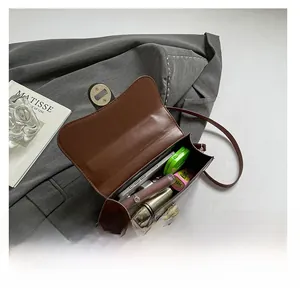 Interior view of brown leather crossbody bag showing phone, lipstick and makeup storage