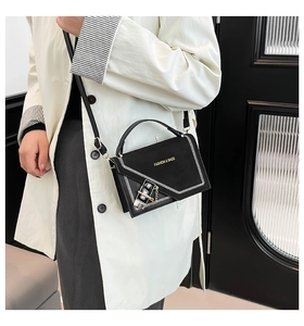 Detail of black square bag featuring white contrast stitching and gold metal buckle