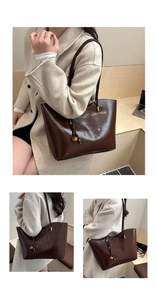 Detail view of large dark brown oil wax leather tote bag with elegant gold bell charm