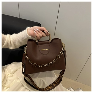 Detail of dark brown PU leather bucket bag with metal handle and gold chain strap