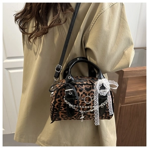Detail of leopard print crossbody bag featuring metal chains and white lace bow