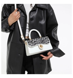 Close-up of white crossbody bag with grey leopard print flap and gold twist lock