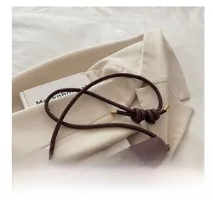 Detail of dark brown leather crossbody bag featuring a knotted strap and gold twist lock