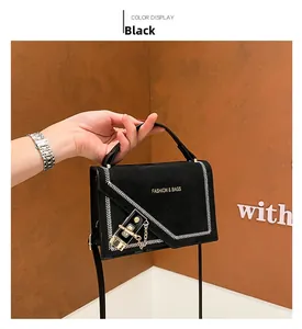 Detail of black crossbody bag with white V-stitching and gold logo lettering on matte finish