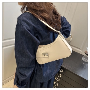 Detail view of cream crescent shoulder bag with silver buckle and glossy leather texture