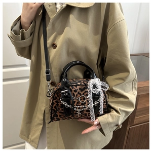 Detail of leopard print Boston bag with silver chain and white lace bow decoration