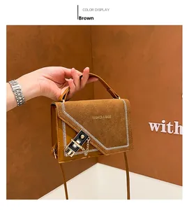 Detail of brown suede bag showing metal clasp, gold chain, and white contrast stitching