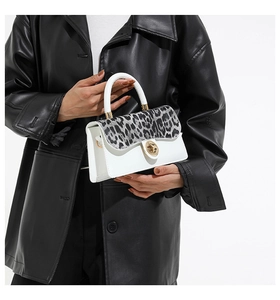 Detail of leopard print flap crossbody bag with gold hardware on a leather coat background