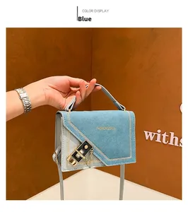 Close-up of blue crossbody bag featuring a metal lock buckle and gold chain detail