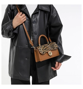 Detail of a leopard print flap bag with a gold clasp paired with a black leather jacket