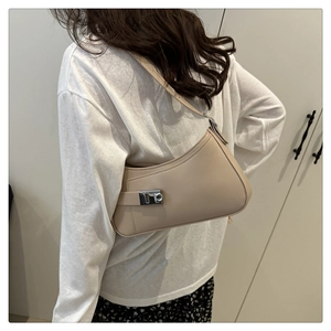 Close-up of beige minimalist hobo bag with silver buckle worn on shoulder