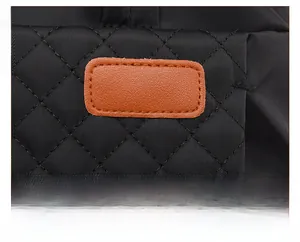 Détail du tissu matelassé noir avec patch en cuir marron et coutures soignées du sac