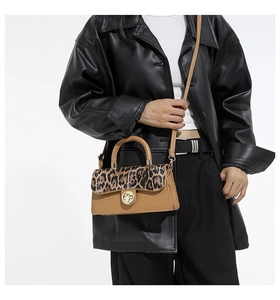 Detail of leopard print flap and golden metal clasp on a brown leather crossbody bag