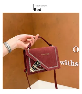 Detail view of burgundy crossbody bag with gold lock buckle and V-shaped stitching