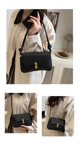 Detail of black crossbody bag featuring a gold capsule clasp and knotted shoulder strap