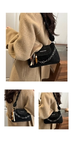 Détail du sac sous le bras en daim noir avec bandoulière tressée et chaîne en perles de bois