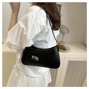 Detail of a black minimalist shoulder bag with a silver metal buckle and slim strap