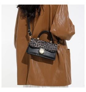 Detail of leopard print crossbody bag with gold lock buckle and black leather shoulder strap
