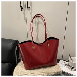 Close-up of a red oil wax leather tote bag featuring gold hardware and large capacity